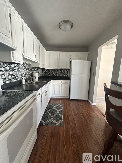 A kitchen with white cabinets and a black counter top.