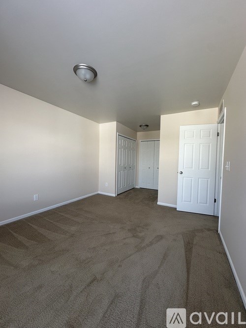 A room with carpeted floor and two doors.