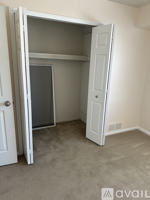 A white door is open to reveal a small, empty room with a carpeted floor.