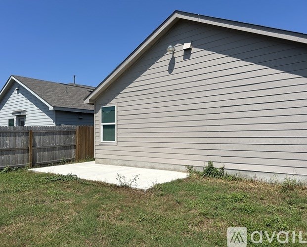 A house with a grey siding and a brown fence.