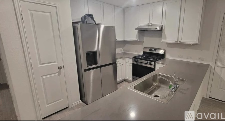 A kitchen with a stainless steel refrigerator, stove, and sink.