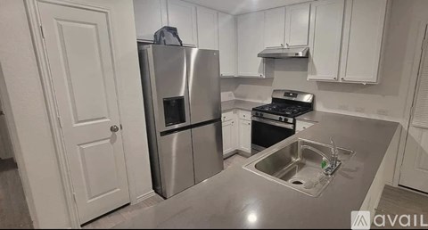A kitchen with a stainless steel refrigerator, stove, and sink.