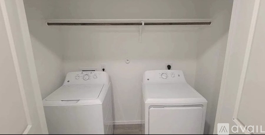 Two white washing machines in a small laundry room.