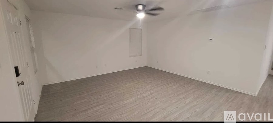 A room with a ceiling fan and light fixture, and a door with a black handle.