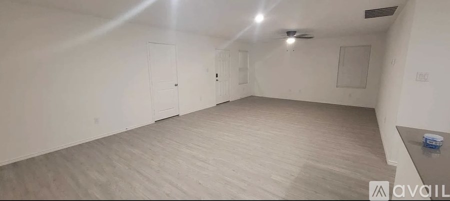 A spacious room with a light-colored floor and walls, and a ceiling fan.