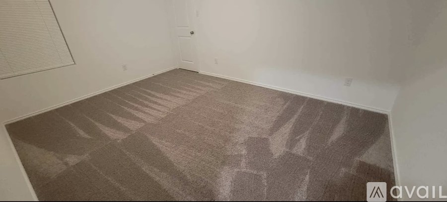 A room with a carpeted floor and a window with blinds.