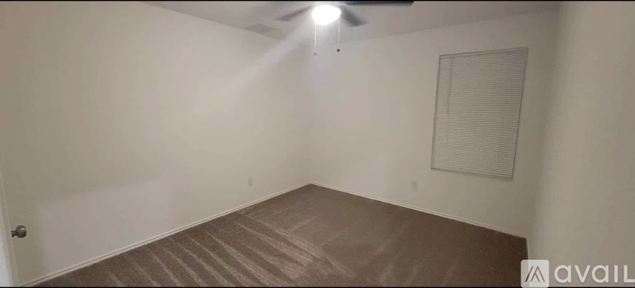 A room with a carpeted floor and a ceiling fan.