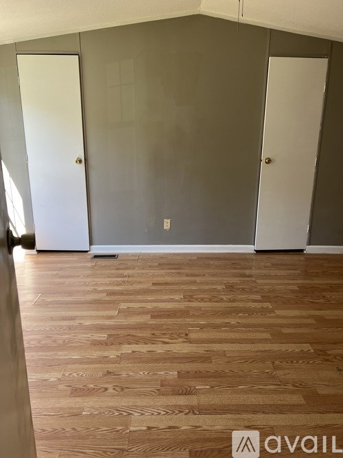 A room with wooden flooring and three doors.