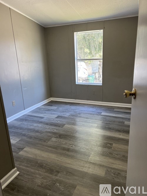 A room with wooden flooring and a window showing an outdoor scene.
