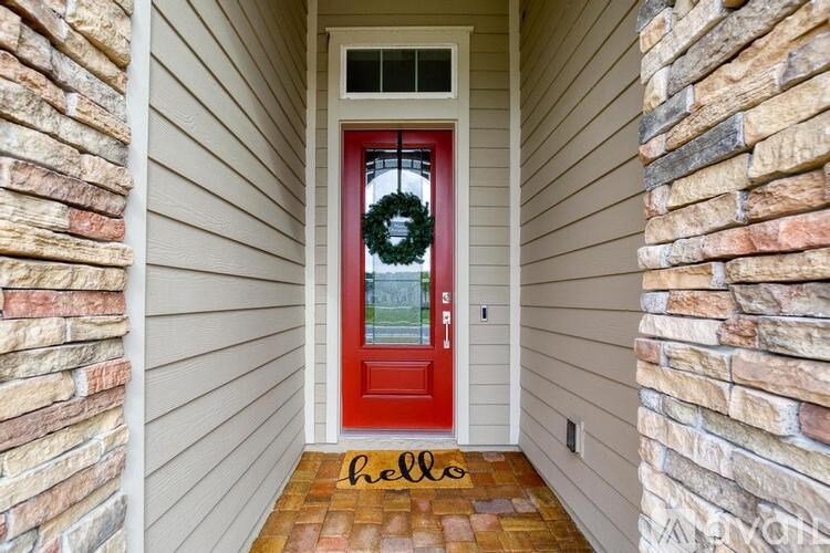 A red door with a wreath and a "hello" doormat.