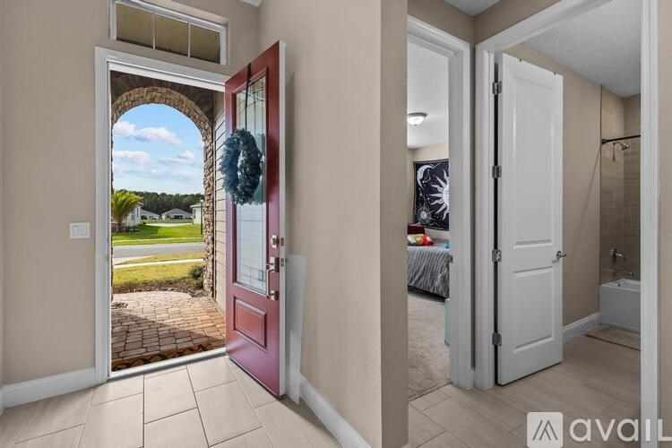 A red door opens to a patio with a brick walkway.