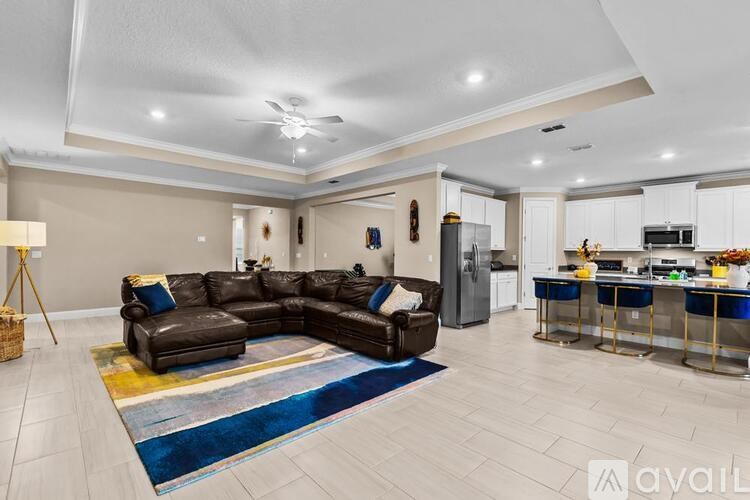 A living room with a brown leather sofa and a kitchen in the background.
