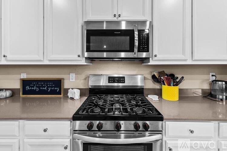 A kitchen with a stove, microwave, and white cabinets.