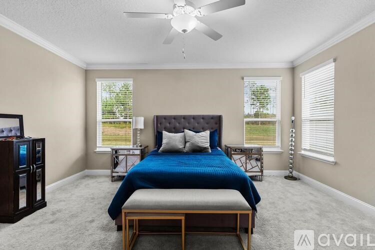 A bedroom with a blue bed and a ceiling fan.