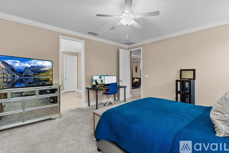A bedroom with a blue bed and a television in the corner.