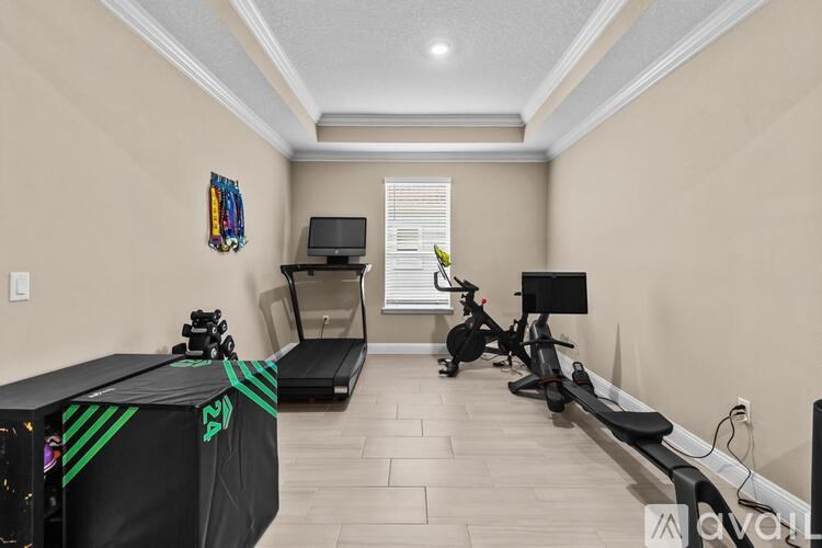 A room with a treadmill, exercise bike, and a television.