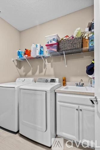 A small laundry room with a washer and dryer and a shelf above them.