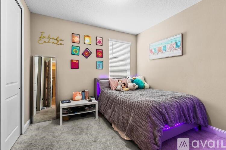 A bedroom with a bed, nightstand, and a wall with pictures and a name written on it.