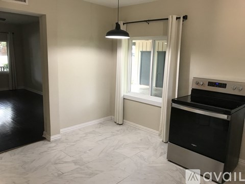 A kitchen with a black stove top oven and a window with curtains.