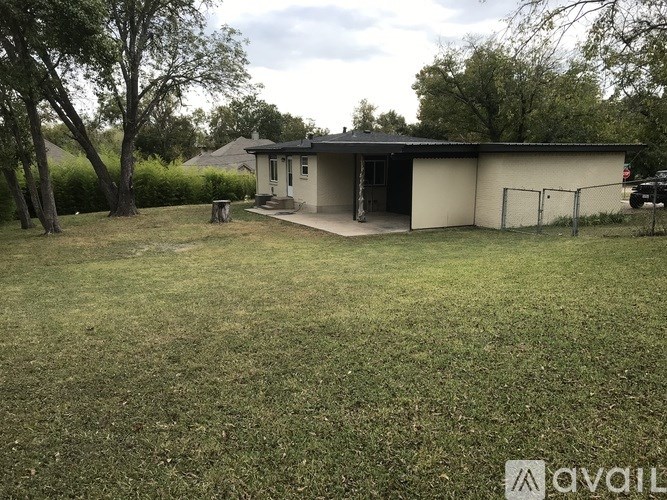 A small house with a fence and a tree in front of it.