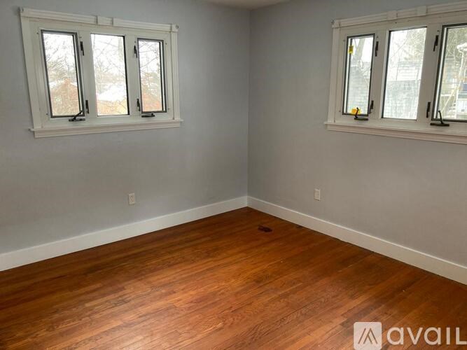 A room with wooden floors and two windows.