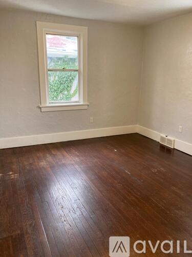 A room with a window and wooden flooring.