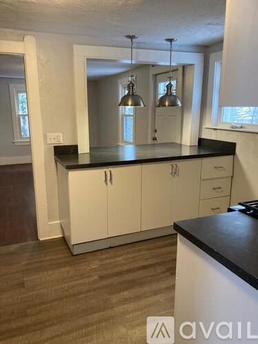 A kitchen with white cabinets and a black countertop.
