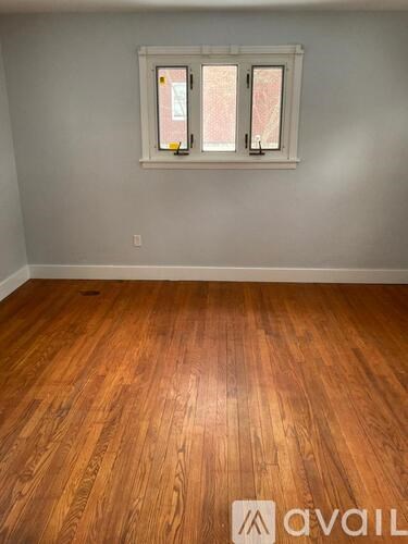 A room with wooden flooring and a window with a white frame.