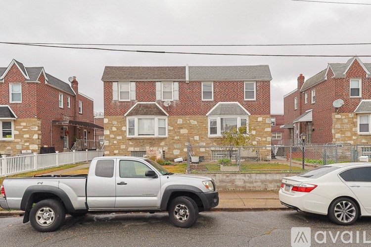 A silver pickup truck is parked in front of a red brick house.