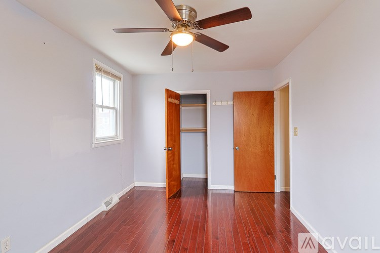 A room with a ceiling fan and wooden floors.