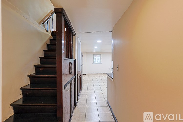 A hallway with a staircase on the left and a door on the right.