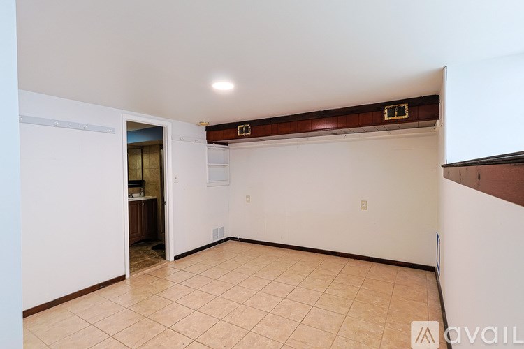 A room with a white wall and a brown wooden strip on the ceiling.