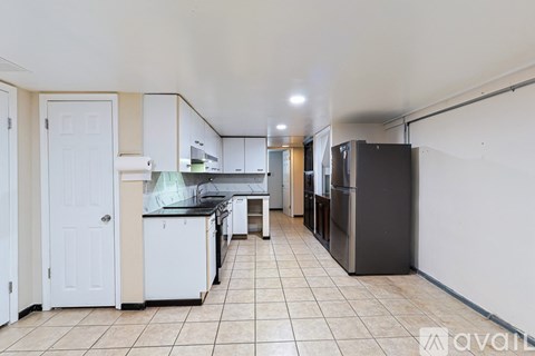 A kitchen with white cabinets and a black fridge.