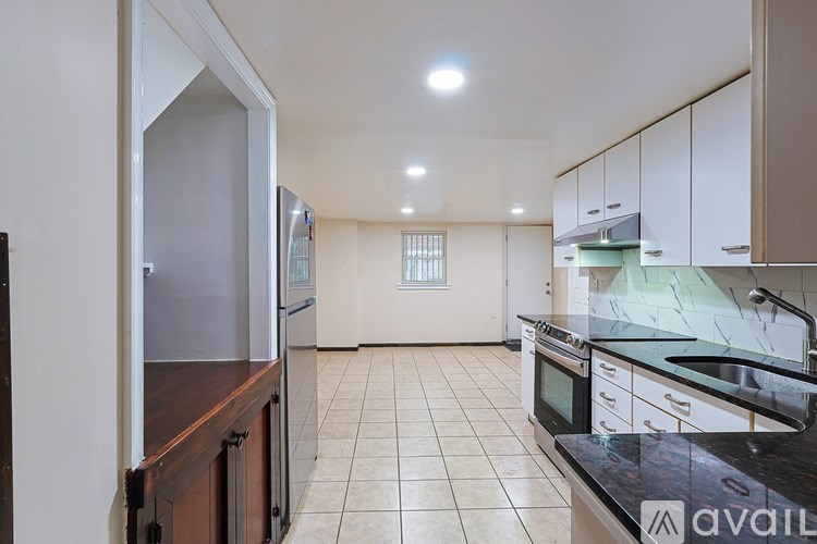 A kitchen with white cabinets and a black countertop is available for rent.