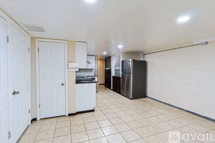 A kitchen area with white cabinets and a black refrigerator.
