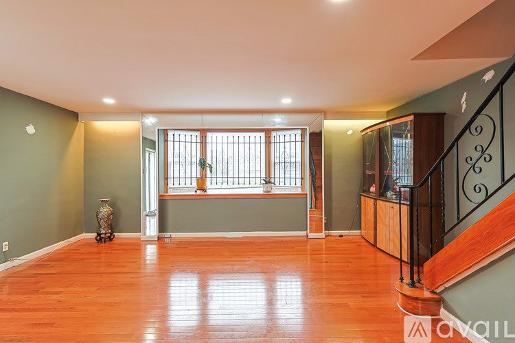 A room with wooden floors and a staircase with a black railing.