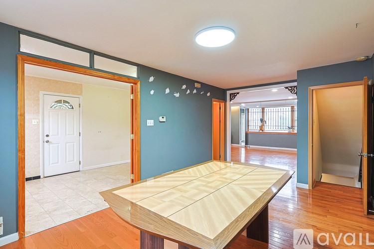 A room with a wooden table in the middle and a white door in the background.