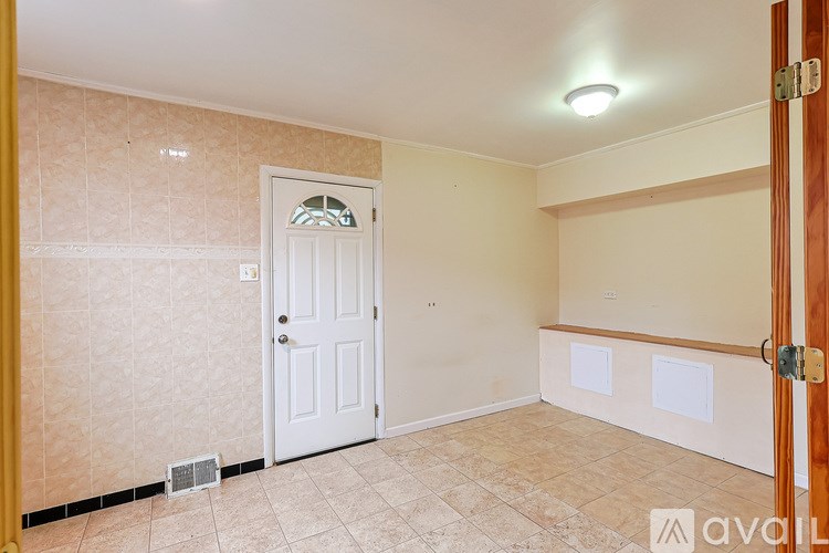 A room with a white door and a tiled floor.