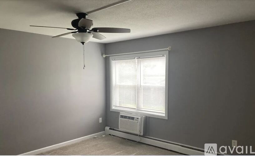 A room with a ceiling fan and a window with blinds.