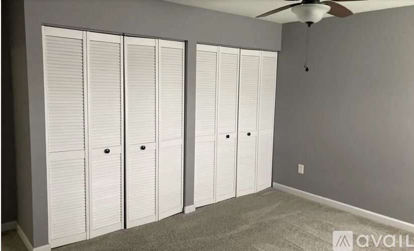 A room with a carpeted floor and a ceiling fan.