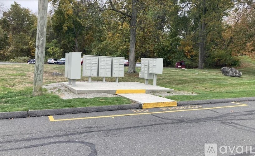 A sign with information is displayed on a stand in a grassy area beside a road.