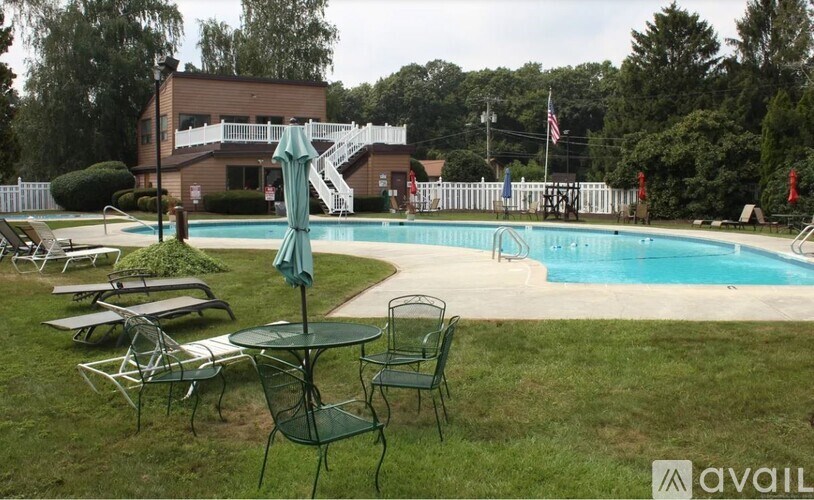 A pool area with chairs and a table with a blue umbrella.