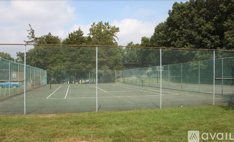 A tennis court surrounded by a fence and trees.