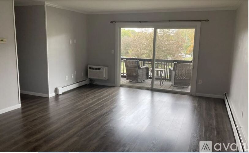 A spacious living room with hardwood floors and a sliding glass door leading to a balcony.