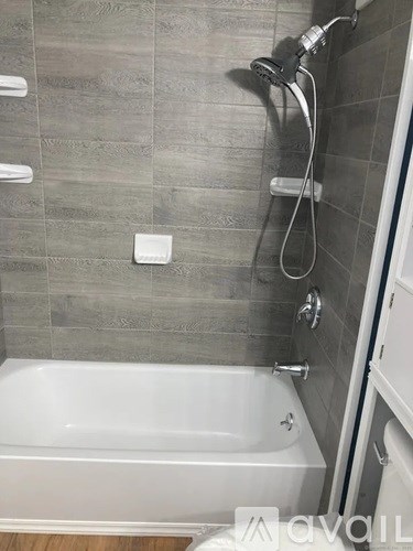 A white bathtub is in a bathroom with grey tiles.
