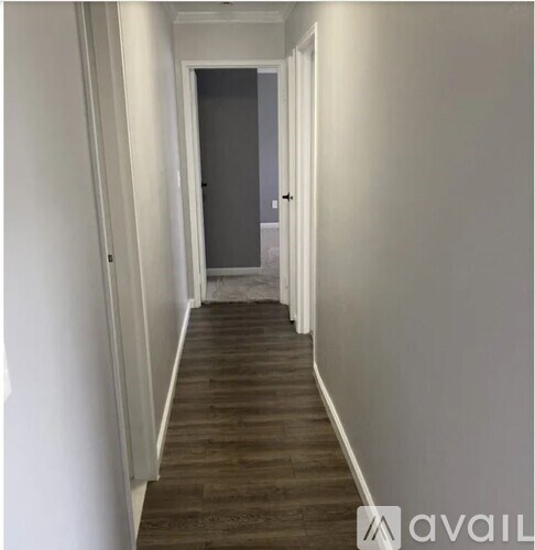 A long hallway with wood flooring and white walls.
