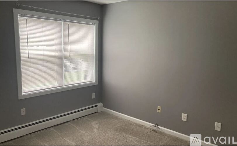 A room with a window and a carpeted floor.