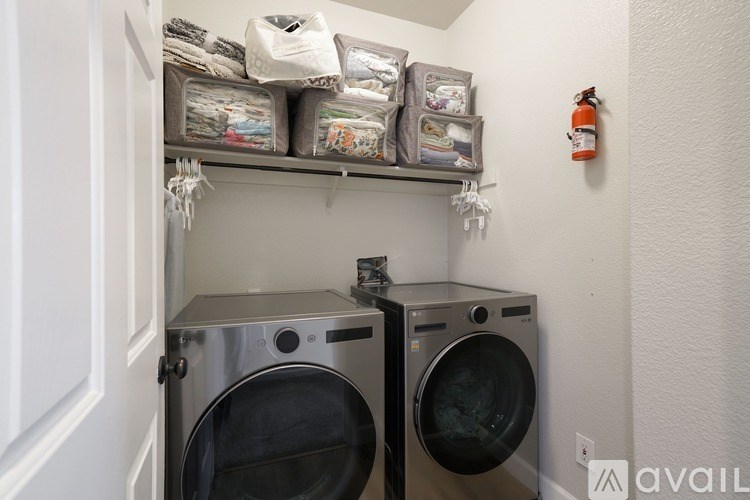 A laundry room with two washing machines and storage bins above them.