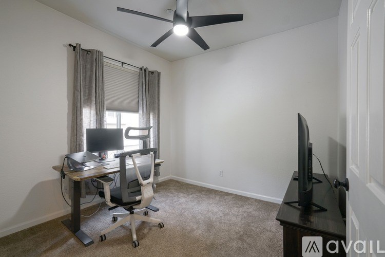 A room with a desk, chair, and television.
