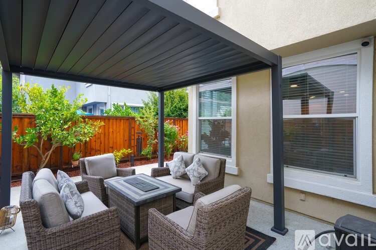 A patio with a table and chairs under a roof.